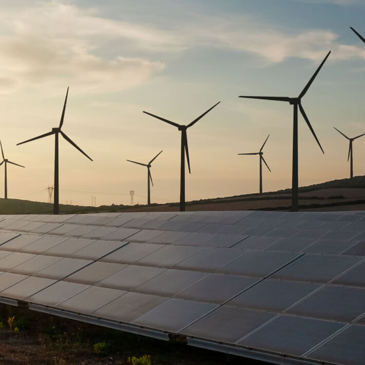 Energia rinnovabile e innovazione sostenibile rappresentate da pannelli fotovoltaici e pale eoliche.